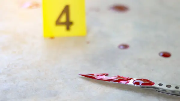 stock image A bloodstained stainless steel knife lying on a concrete floor, with a blurred yellow number 4 sign nearby and blood splatter surrounding the scene, evoking a sense of crime investigation.