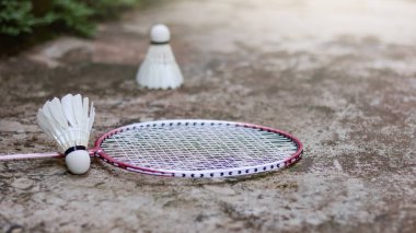 Egzersiz yapmayı geliştirmek için beyaz badminton topları ve badminton raketleri koyu arka planda.