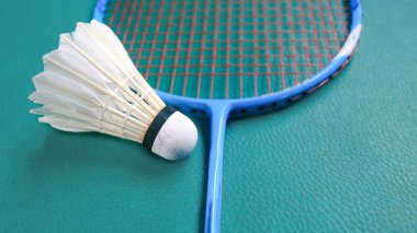 White badminton shuttlecocks and badminton rackets on green floor indoor badminton court. Concept for badminton competition and its lovers. clipart