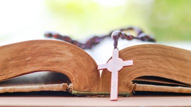 Koyu kırmızı bakır haç, Hristiyanlar arasında İsa 'nın sevgisini ve Hıristiyan öğretilerinin önemini yansıtan açık bir kitabın yayılmasını simgeliyor..