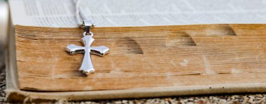 Eski açık bir kitaba dayanan parlak metal haç Hristiyanlar arasında İsa 'nın sevgisinin yayılmasını simgeliyor. İnanç bağlılığını ve Hıristiyan öğretilerinin önemini yansıtıyor..