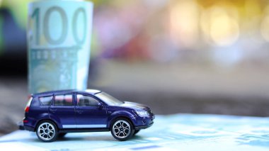 Arka planda avro banknotları olan model bir araba. Araba, araba kredisi ve araba sigortası için tasarruf planlama.