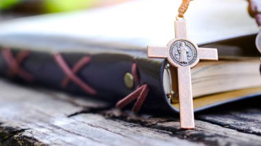 Koyu kırmızı bakır haç, Hristiyanlar arasında İsa 'nın sevgisini ve Hıristiyan öğretilerinin önemini yansıtan açık bir kitabın yayılmasını simgeliyor..