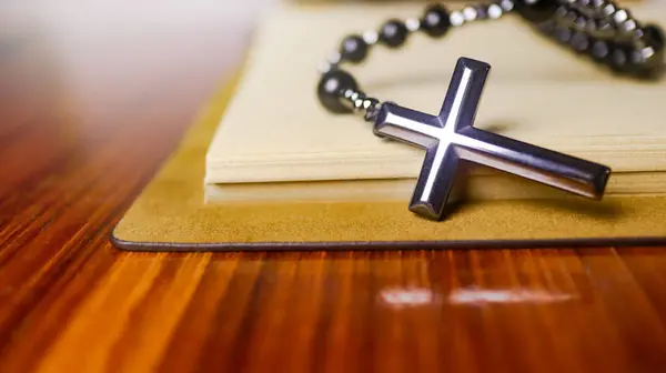 Hristiyanlar arasında İsa 'nın sevgisinin yayılmasını simgeleyen eski açık bir kitabın üzerindeki Dark Metal haçı Hıristiyanların bağlılığını ve Hıristiyan öğretilerinin önemini yansıtıyor..