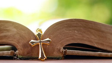 Hristiyanlar arasında İsa 'nın sevgisinin yayılmasını simgeleyen eski açık bir kitabın üzerindeki altın metal haç inançlarını ve Hıristiyan öğretilerinin önemini yansıtıyor..