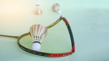 Kırık badminton raketi açık yeşil bir yüzey üzerinde bir mekik horozu, dayanıklılık ve sportmenlik.