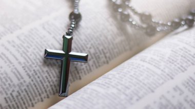 Eskimiş bir kitabın üzerine koyulmuş koyu kahverengi bir haç. Güç, inanç ve dayanıklılığı simgeliyor..