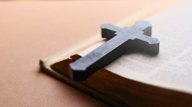 Eskimiş bir kitabın üzerinde duran koyu kahverengi ahşap haç inancı, bilgeliği ve maneviyatı simgeliyor..