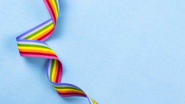 Mavi pastel arka planda renkli gökkuşağı şeridi. Dünyanın dört bir yanındaki LGBT topluluklarına tezahürat yapma kavramı