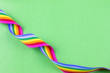 Yeşil pastel arka planda renkli gökkuşağı şeridi. Dünyanın dört bir yanındaki LGBT topluluklarına tezahürat yapma kavramı