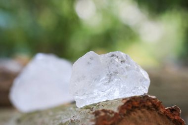 Bulanık arka planı olan tahta bir kütüğe yerleştirilmiş beyaz alum kristali. Kırsal ve organik ortamda geleneksel doğal çözüm..