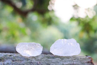 Bulanık arka planı olan tahta bir kütüğe yerleştirilmiş beyaz alum kristali. Kırsal ve organik ortamda geleneksel doğal çözüm..