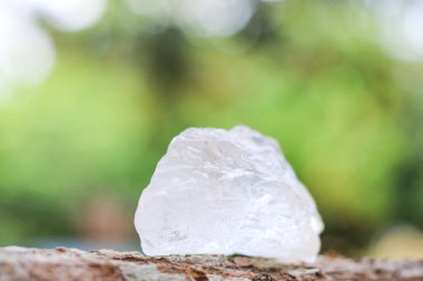 Bulanık arka planı olan tahta bir kütüğe yerleştirilmiş beyaz alum kristali. Kırsal ve organik ortamda geleneksel doğal çözüm..