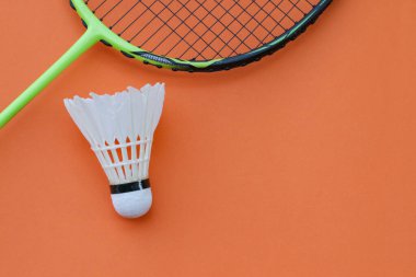 Saf turuncu arka planda bir badminton raketi. Kavram: Cesur ve modern renklere sahip dinamik spor yaşam tarzı.