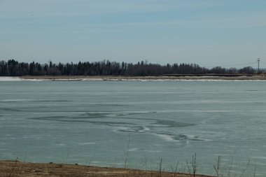 Ice still clings to the top of the lake on an early spring day. Gleniffer Lake PRA, Red Deer County, Alberta, Canada