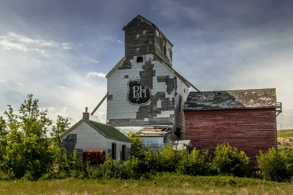 stock image Rustic buildings and grain elevator stand in what used to be the town now a ghost town of Sharples Alberta Canada