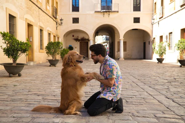 stock image young latino man and his brown golden retriever dog kneeling on the ground while looking at each other with their heads together in sign of affection and love. Concept pets, animals, dogs, pet love.