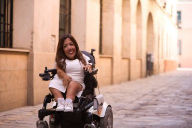 Tekerlekli sandalyedeki genç ve güzel engelli kadın ve hareket kabiliyetinin azalması tatilde olduğu şehirde gezinin keyfini çıkarıyor..