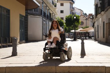 Tekerlekli sandalyedeki engelli genç bir kadın hareket kabiliyeti düşük bir mimari engelle karşılaşır ve yoluna devam etmesinin önünde bir engel vardır..