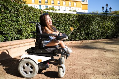 Tekerlekli sandalyedeki genç kadın ve parkta çalışan dizüstü bilgisayarıyla hareket kabiliyeti azaldı..