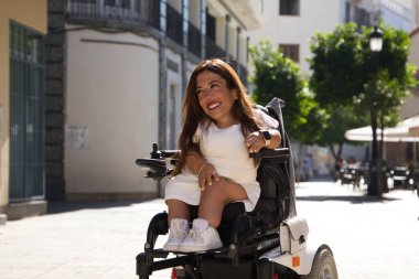 Tekerlekli sandalyedeki genç ve güzel engelli kadın ve hareket kabiliyetinin azalması tatilde olduğu şehirde gezinin keyfini çıkarıyor..