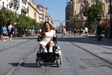 Tekerlekli sandalyedeki genç ve güzel engelli kadın ve hareket kabiliyetinin azalması tatilde olduğu şehirde gezinin keyfini çıkarıyor..