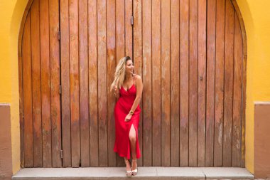 Ahşap bir kapının arka planında kırmızı ipek elbiseli genç ve güzel bir kadın saçına dokunuyor ve değişik yerlere bakarak farklı ifadeler takınıyor. İfadeleri ve jestleri kavra