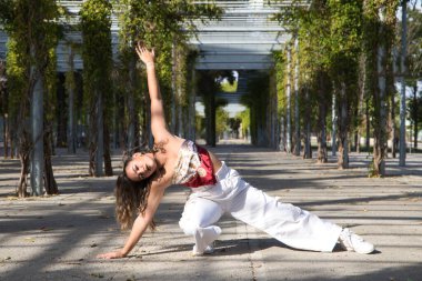 Latin kadın, genç ve güzel dans eden modern dans parktaki sokakta ve farklı ifadeler ve duruşlar sergiliyor. Konsept dansı, hip hop, dans, sanat, aksiyon, güzellik, gençlik sanatı.