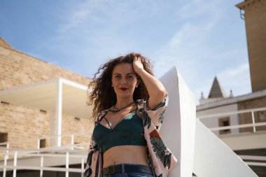 Güzel bir genç kadın, kıvırcık saçlı ve mavi gözlü sarışın Cadiz, İspanya 'yı gezerken metal bir yapıya yaslanıyor..