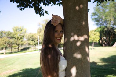 Genç, güzel, sarışın, mavi gözlü kadın ağaca yaslanıyor. Kadın farklı ifadeler kullanır, yorgun, üzgün, mutlu, neşeli, melankolik, nefret, keder. İfadeleri kavra.