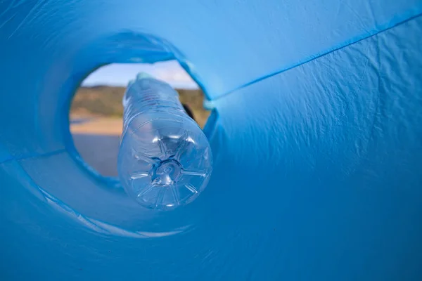 Detail of a volunteer\'s hand putting a plastic bottle in the bag. Photo taken from below. Concept of Earth Day and World Environment Day June 5.