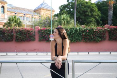 pretty young Spanish woman looking over the railing to the horizon. The woman is happy and content because she looks to the future with interest.