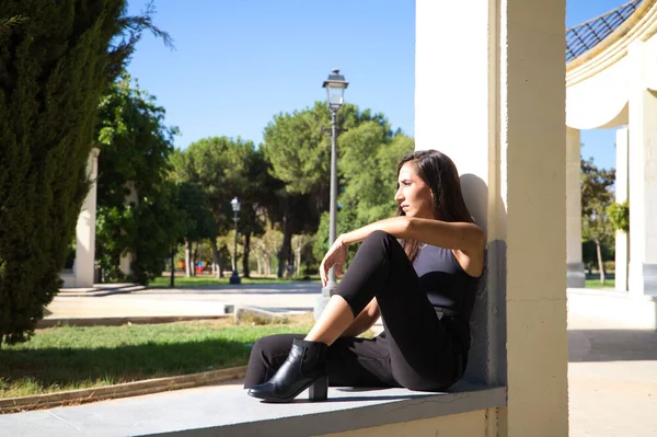 公園に座っている美しい 暗い髪のスペイン人女性 女はどこにも見ていないと黒の服を着ています — ストック写真