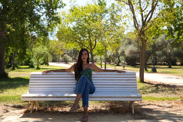 黒い髪の美しいスペイン人女性が公園の白いベンチに座っています 彼女は一人で寛大だ 概念表現とジェスチャー — ストック写真
