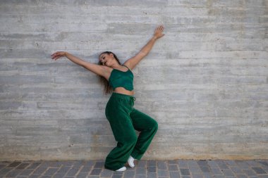 Latin kadın, genç ve güzel dans eden modern dans sokaktaki gri çimento arka planında farklı ifadeler ve duruşlar sergiliyor. Konsept dansı, hip hop, dans, sanat, aksiyon, gençlik sanatı.