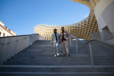 Young gay married couple are walking down a flight of stairs holding hands as they stroll through Seville. The couple is happily married. Concept of gay and lesbian rights