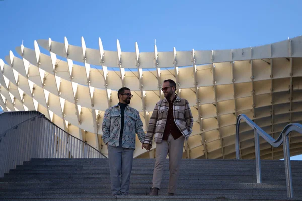 Young gay married couple are walking down a flight of stairs holding hands as they stroll through Seville. The couple is happily married. Concept of gay and lesbian rights
