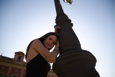 Genç bir kadın kafasını sokak lambasına yaslamış üzgün üzgün bakıyor. Kadın sersemlemiş ve depresyonda..