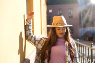 Tek kolu sarı duvarda olan şapkalı güzel bir İspanyol kadın. Kadın mutlu..