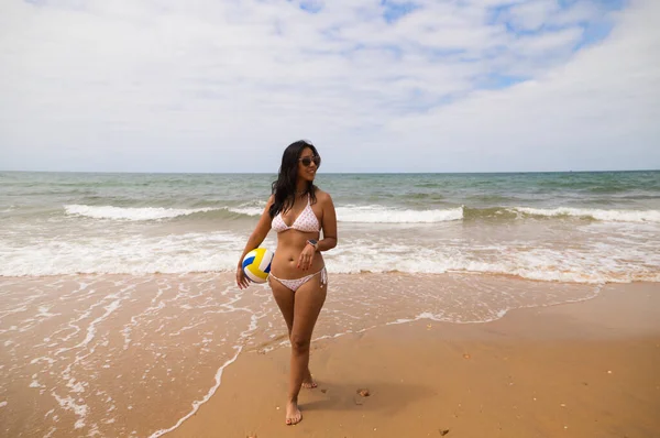 ビーチには 若く美しいラティーナの女性がサングラスをかけています 女は海岸にいてバレーボールをしている 夏で暑いですね 休日や旅行のコンセプト スポーツ — ストック写真