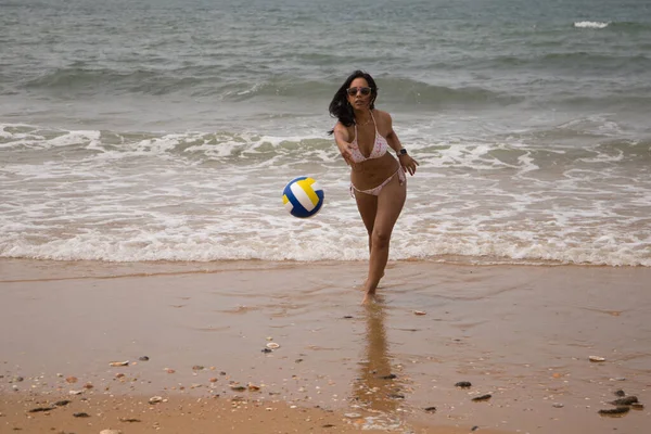 해변에 선글라스를 아름답고 레지나라는 있습니다 해변에서 카메라에 배구를 던지고 있습니다 — 스톡 사진