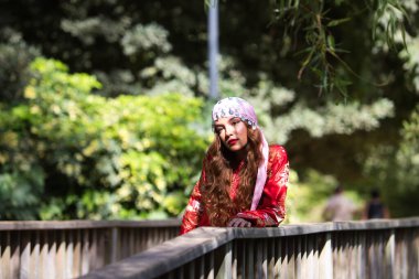 Güzel bir Faslı kadın geleneksel bir Fas elbisesi giyer kırmızı ve gümüş işlemeli, kafasına pembe bir göbek dansı eşarbı takar. Kadın rahat ve mutlu..