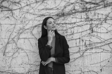 Duvara yaslanmış, hüzünlü, melankolik, mutlu, bitkin, sersemlemiş, gülümseyen, düşünen, yorgun bir kadının siyah beyaz portresi. Farklı ifadeleri kavra.