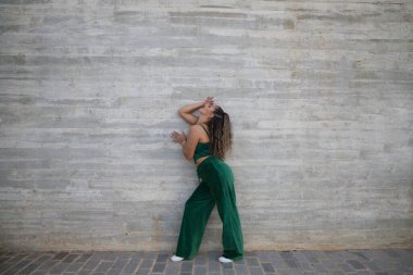 Latin kadın, genç ve güzel dans eden modern dans sokaktaki gri çimento arka planında farklı ifadeler ve duruşlar sergiliyor. Konsept dansı, hip hop, dans, sanat, aksiyon, gençlik sanatı.