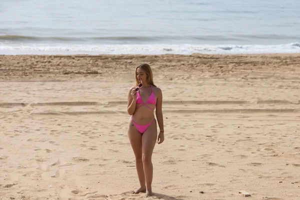 비키니입고 선글라스를 금발의 해변을 거닐고 있어요 여자는 휴가를 즐기며 바다를 — 스톡 사진