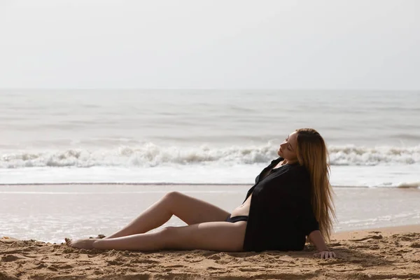 해변에 아름다운 금발의 여자는 일몰을 즐기면서 휴식을 취하고 여자는 진지하고 — 스톡 사진