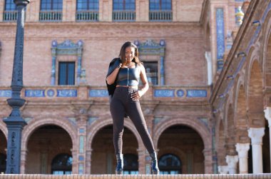 Genç ve güzel siyah Latin kadın Seville şehrinin en önemli meydanını ziyaret ediyor. Kadın uluslararası moda etkinliklerinin yapıldığı meydanın merdivenlerinden iniyor..