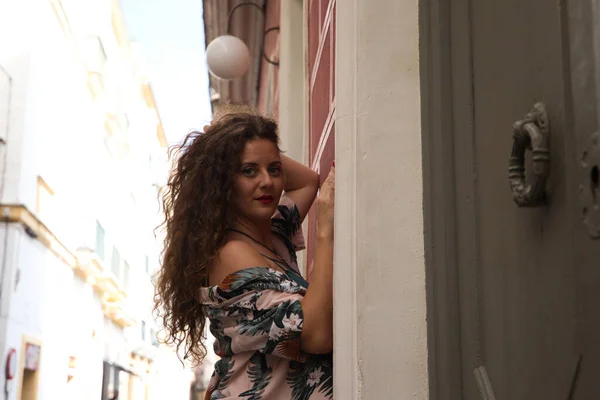 カメラを見て官能的な方法で写真のための通りのポーズの壁にもたれて巻き毛と青い目を持つ美しい女性 若いとブロンド 女性はスペイン ヨーロッパで休暇中です — ストック写真