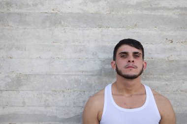 Young handsome man in white t-shirt making different expressions in front of grey wall. Man is happy and smiling. Concept different expressions.