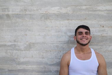 Young handsome man in white t-shirt making different expressions in front of grey wall. Man is happy and smiling. Concept different expressions.